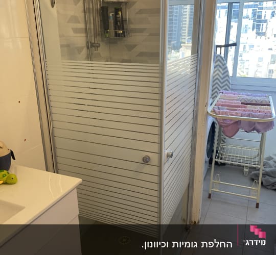 מקלחון פינתי זכוכית עם דלתות הזזה ועיטור פסים חלביים